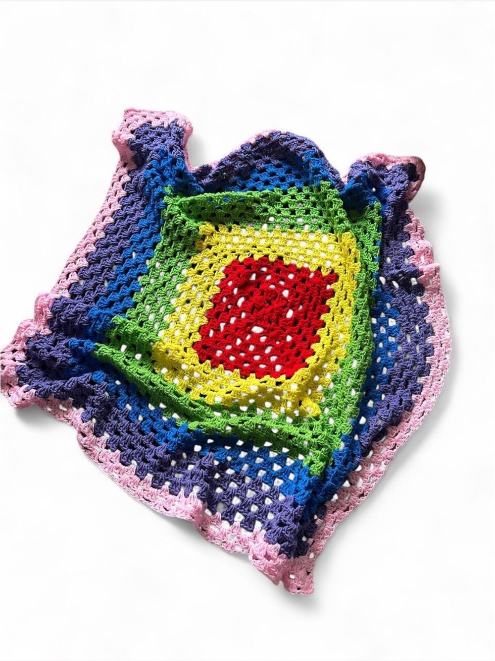 Handmade crochet blanket with red, yellow, and green concentric circles on a blu